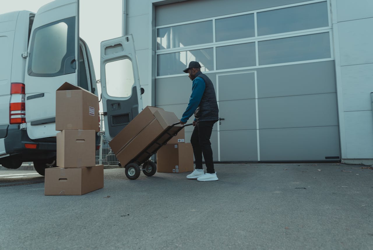 Courier unloading packages from a delivery van at a warehouse entrance. Efficient distribution.